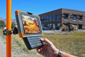 Construction worker using a Juniper Systems rugged device under sunny, humid conditions on-site.